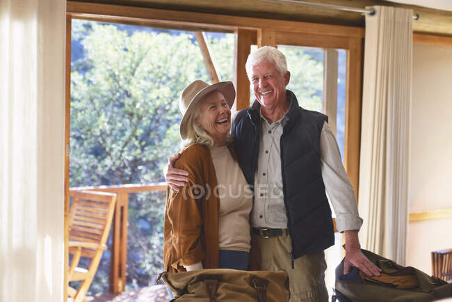 Despreocupada pareja de ancianos riendo en la habitación de hotel - foto de stock