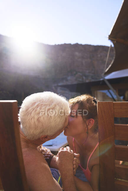 Feliz romántica pareja mayor besándose en el balcón soleado - foto de stock