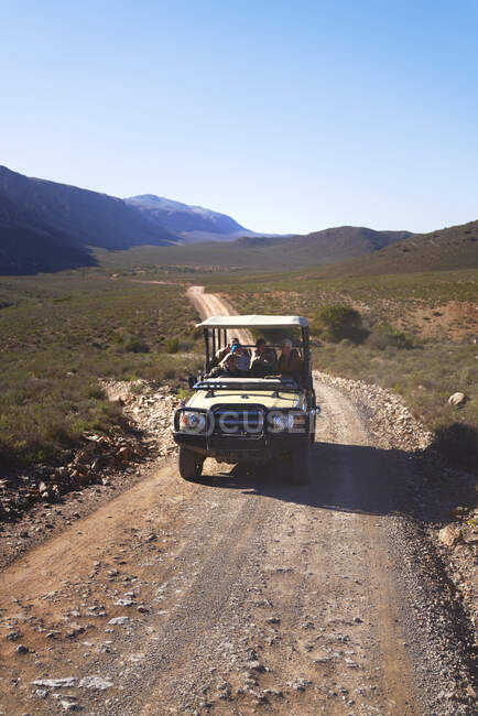 Safari off-road vehicle driving along sunny remote road South Africa — Stock Photo