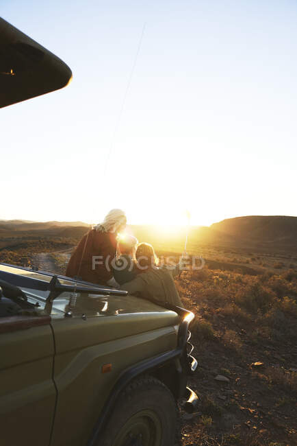 Amigos en safari disfrutando de la escénica salida del sol Sudáfrica - foto de stock