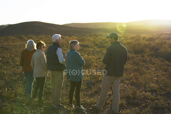Safari guía turístico hablando con el grupo en los pastizales soleados de Sudáfrica - foto de stock