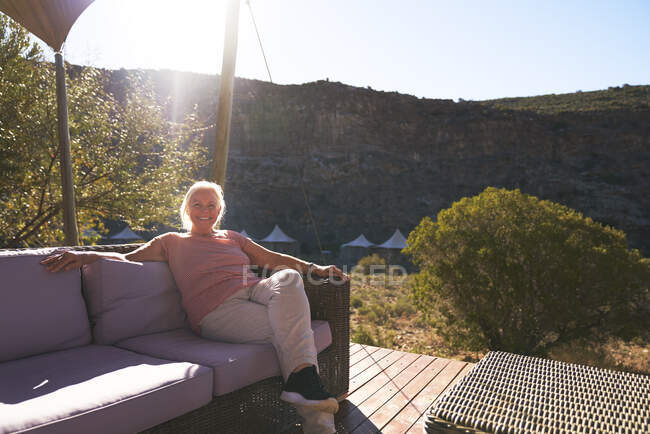 Mulher sênior despreocupada relaxando no ensolarado safari lodge varanda — Fotografia de Stock