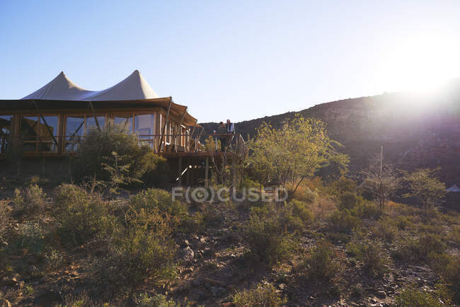 Pareja mayor relajándose en el soleado safari lodge hotel balcón - foto de stock