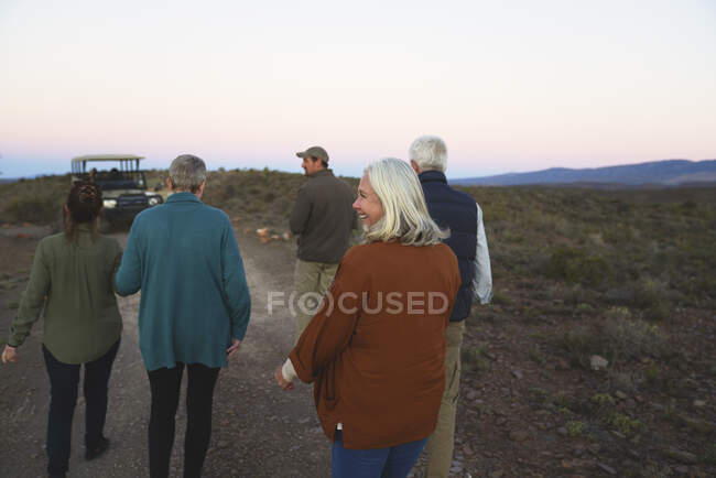 Felice donna anziana in safari di ritorno al veicolo con gruppo — Foto stock
