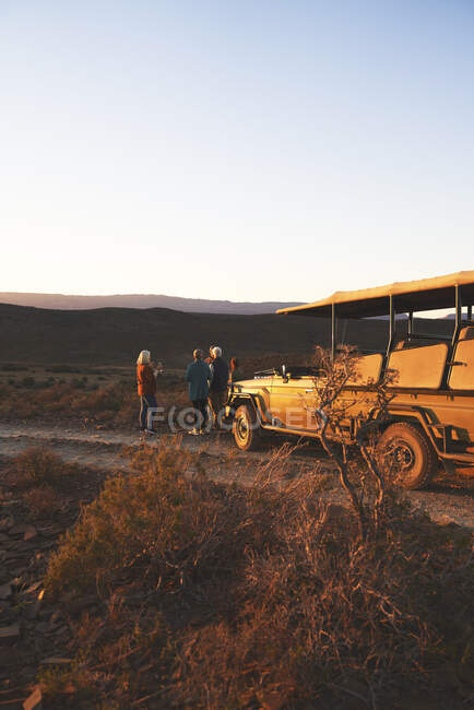 Safari grupo turístico y vehículo todoterreno en la carretera al atardecer Sudáfrica - foto de stock