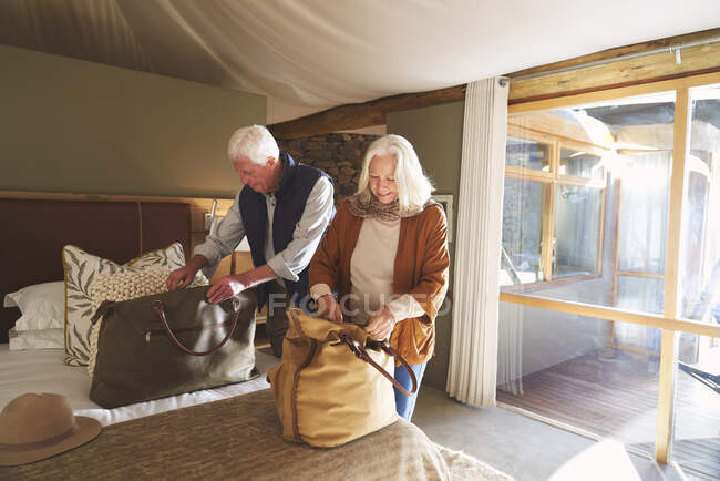Seniorenpaar packt im Hotelzimmer Koffer aus — Stockfoto