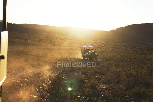 Safari off-road vehicle driving on sunny dirt road South Africa — Stock Photo