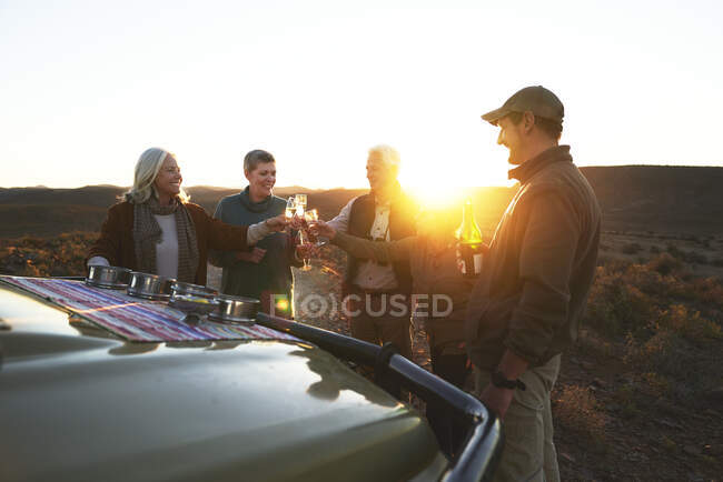 Safari tour grupo tostadas copas de champán en la puesta del sol - foto de stock