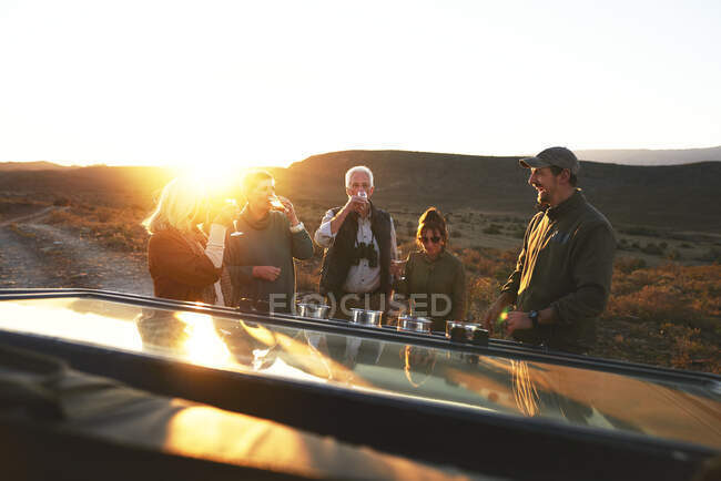 Safari grupo de turismo bebendo champanhe ao pôr do sol — Fotografia de Stock