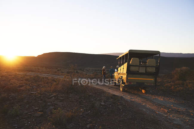 Safari off-road vehicle and tourists at sunset roadside South Africa — Stock Photo