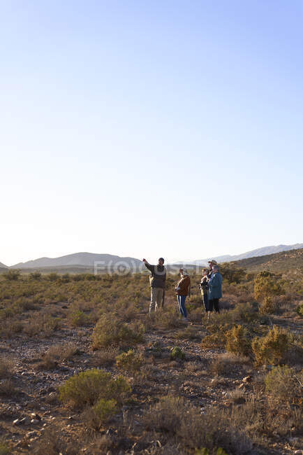 Safari-Reiseleiter unterhält sich mit Gruppe in sonnigem, abgelegenem Grasland — Stockfoto