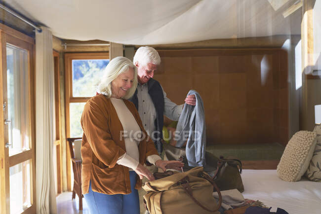 Senior coppia disimballaggio bagagli in camera d'albergo — Foto stock