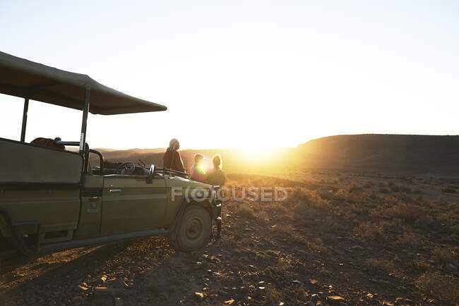 Safari grupo de turistas observando la puesta de sol en vehículo todoterreno Sudáfrica - foto de stock