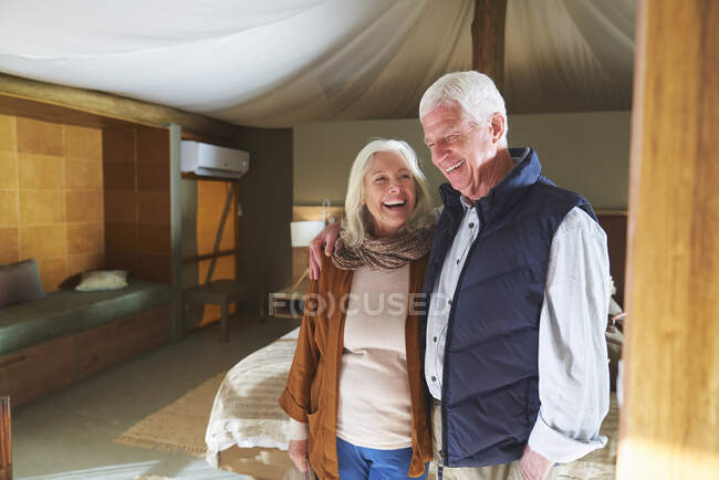 Feliz pareja de ancianos riendo en la habitación del hotel - foto de stock