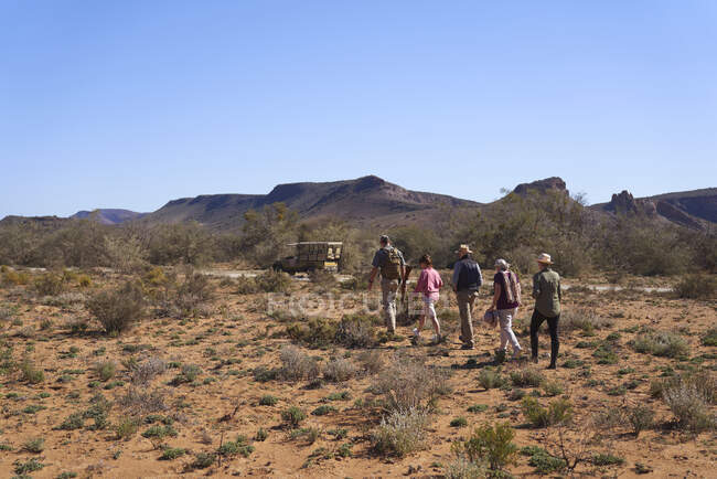 Safari grupo turístico retornando ao veículo off-road ensolarado reserva de vida selvagem — Fotografia de Stock