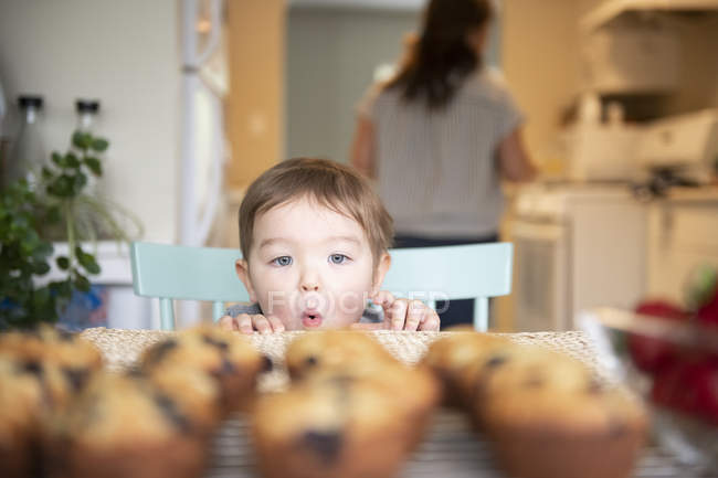 Cute excited girl starting at fresh homemade muffins — Stock Photo