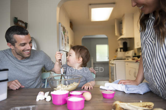 Счастливая молодая семья печет за кухонным столом — стоковое фото