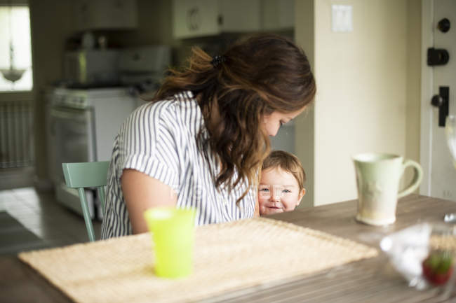 Mother and cute toddler daughter at kitchen table — Stock Photo