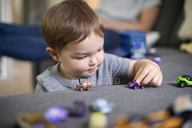 Close up curious toddler girl playing with toy cars — Stock Photo