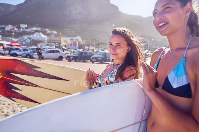 Young women with surfboards on sunny summer beach — Stock Photo