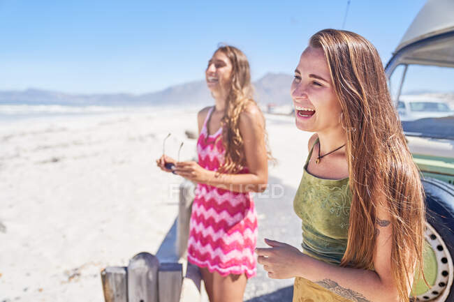 Feliz jóvenes amigas riendo en la playa soleada - foto de stock