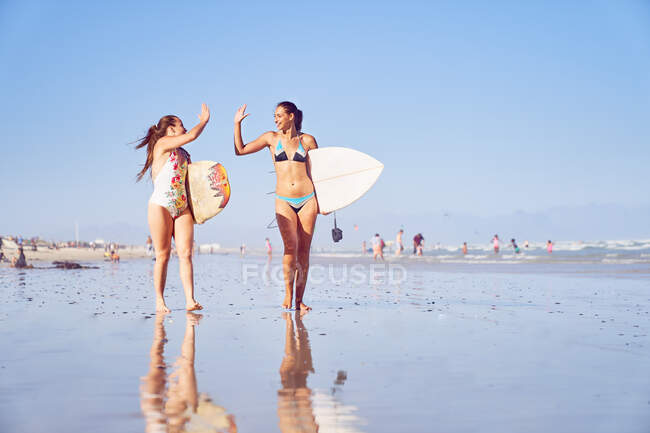 Glückliche junge Surferinnen Freunde High Fiving am sonnigen Strand — Stockfoto