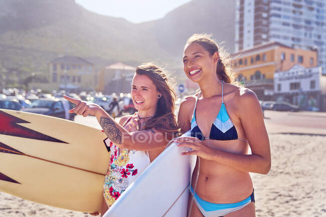 Happy young women female surfers with surfboards on sunny beach — Stock Photo