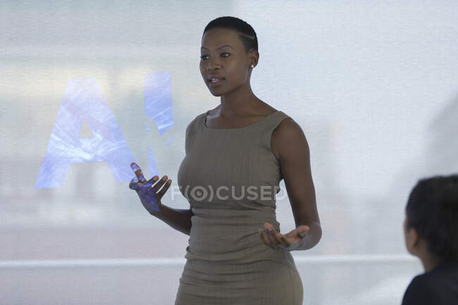 Businesswoman leading meeting at projection screen with AI text — Stock Photo