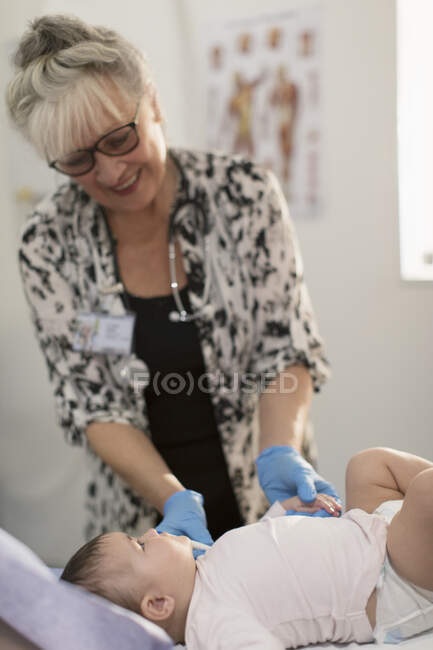 Pediatra femenina examinando a una niña en la sala de examen - foto de stock