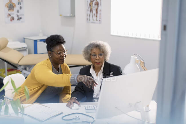 Female doctor and patient meeting at computer in doctors office — Stock Photo