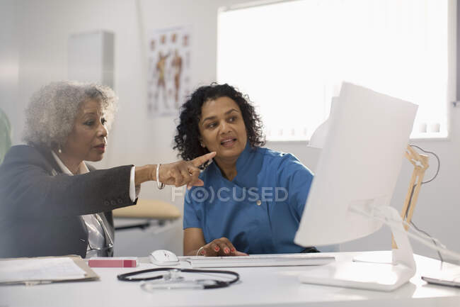 Жінка-лікар і пацієнт, використовуючи комп'ютер в офісі лікарів — стокове фото
