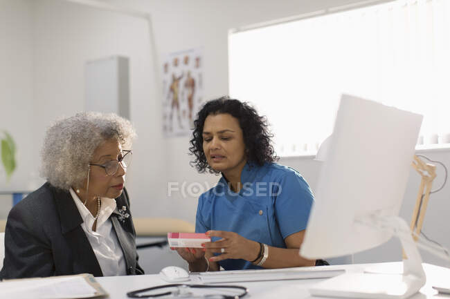 Médica feminina prescrevendo medicação para paciente sênior em consultório médico — Fotografia de Stock