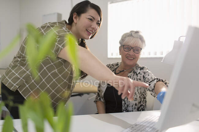 Doctora y paciente usando computadora en consultorio médico - foto de stock