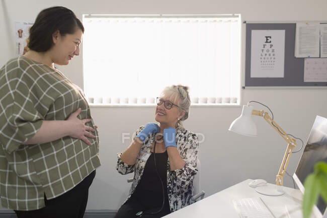 Жінка-лікар, яка вивчає вагітну жінку в кабінеті лікарів — стокове фото
