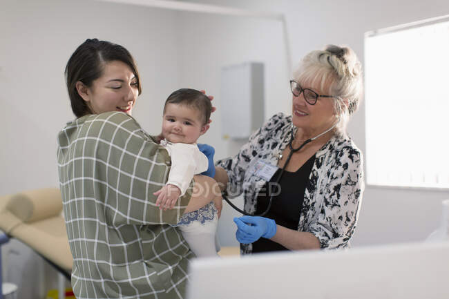 Pediatra femenina examinando a una niña en la sala de examen - foto de stock