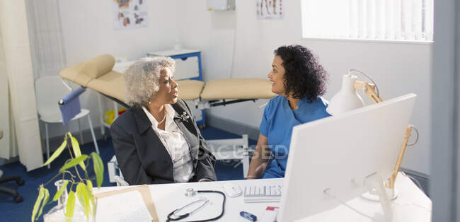 Doctora hablando con paciente senior en consultorio médico - foto de stock
