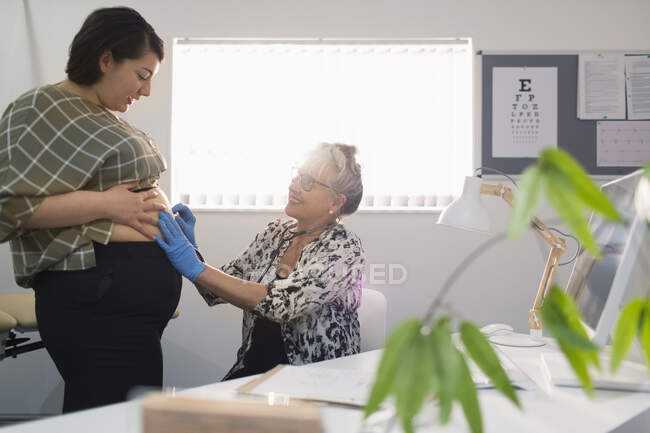 Жінка-лікар оглядає вагітного пацієнта в кабінеті лікарів — стокове фото