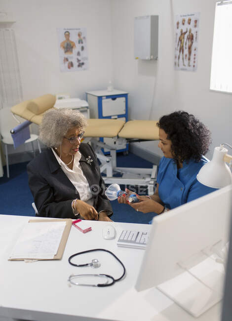 Médica do sexo feminino ensinando paciente sênior como usar inalador em consultório médico — Fotografia de Stock