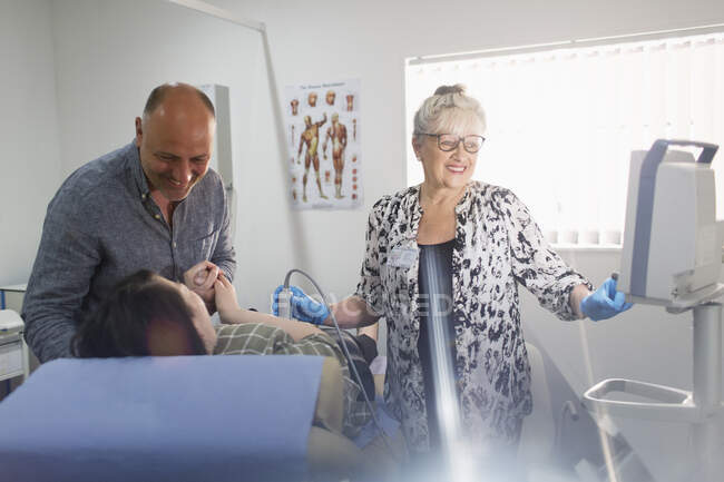 Técnico realizando ultrassom para casal grávida na sala de exame — Fotografia de Stock