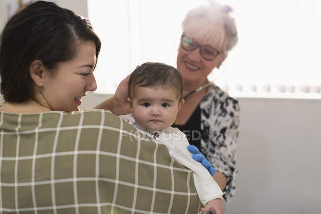 Portrait cute baby girl being examined by pediatrician in doctors office — Stock Photo