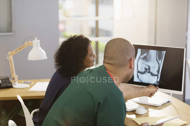 Doctors consulting, examining x-ray at computer in doctors office — Stock Photo