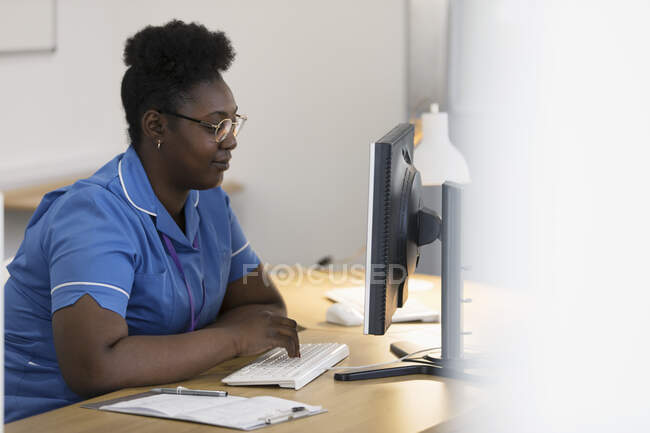 Женщина-медсестра работает за компьютером в офисе врача — стоковое фото