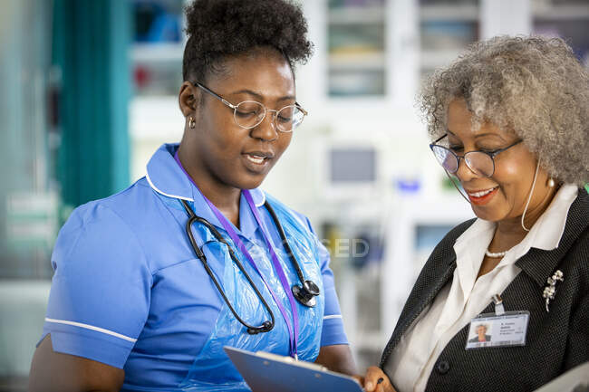 Doctora y enfermera hablando - foto de stock