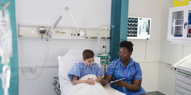Female nurse talking with boy patient in hospital room — Stock Photo