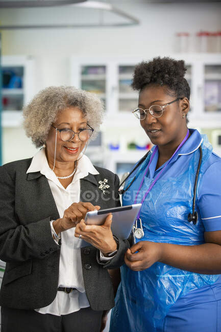 Médecin et infirmière utilisant une tablette numérique en clinique — Photo de stock