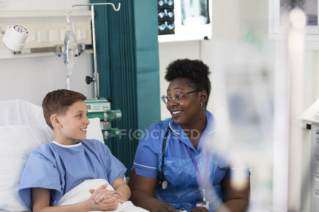 Enfermeira feminina conversando com menino paciente no quarto do hospital — Fotografia de Stock
