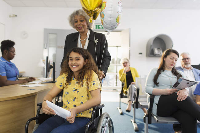 Портрет усміхненої дівчини-пацієнтки в інвалідному візку в клініці — стокове фото