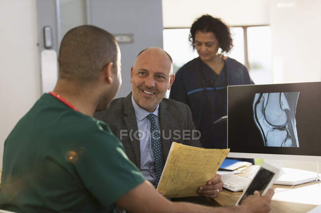 Médecin et infirmière discutant de rayons X numériques à l'ordinateur à la clinique — Photo de stock