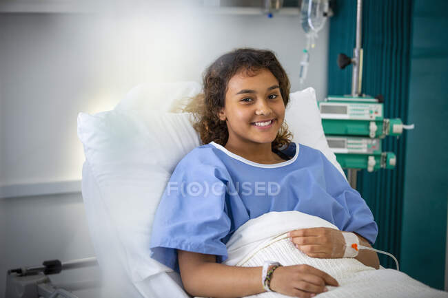 Retrato chica sonriente paciente en cama de hospital - foto de stock