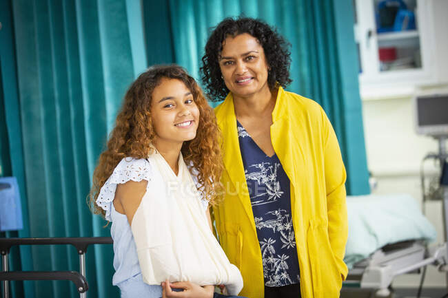 Портрет усміхненої матері і дочки з рукою в слінгу в лікарні — стокове фото